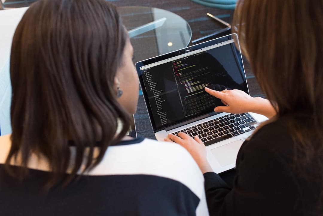 Two people review code on a laptop together.